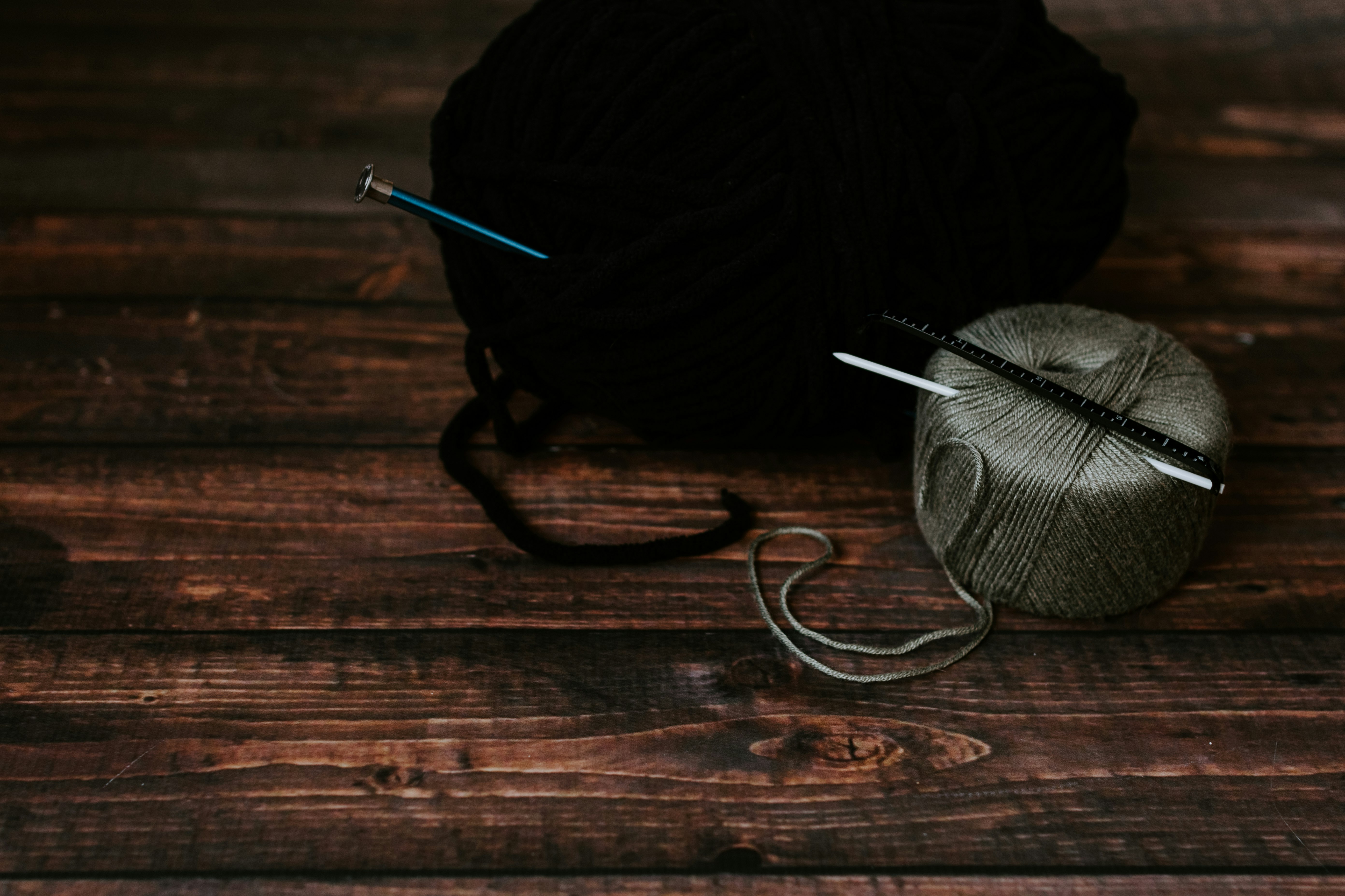 two black and gray yarns on wooden surface